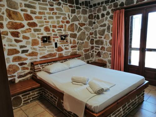 a bed in a room with a stone wall at Athina EcoFarm in Ancient Epidauros