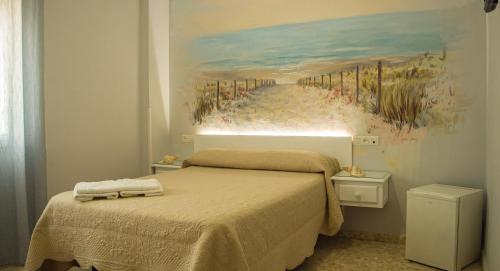 a bedroom with a bed and a painting of a beach at Hostal Patio Andaluz in Punta Umbría