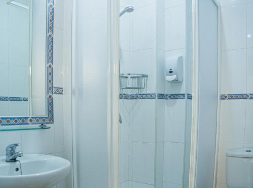uma casa de banho com um chuveiro, um lavatório e um WC. em Hostal Patio Andaluz em Punta Umbría