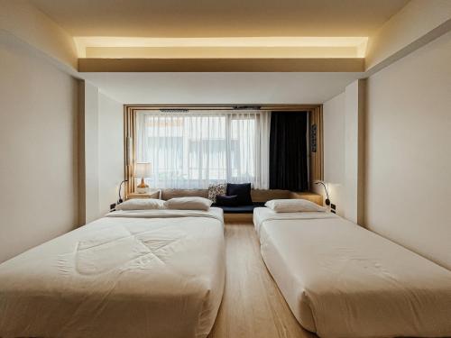 a hotel room with two beds and two windows at NORN Nimman13 Boutique Hotel Chiang Mai in Chiang Mai