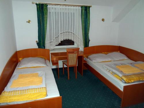 two beds in a room with a table and a desk at Hotel Korona in Słubice