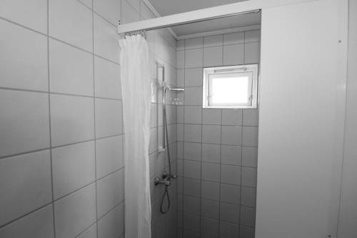 a bathroom with a shower with a curtain and a window at Fossumsanden Camping og Hytter in Fyresdal