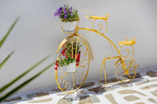 a gold plant stand with flowers on it at Tzane Studios & Apartments - Steps away from Golden Beach in Chrissi Akti