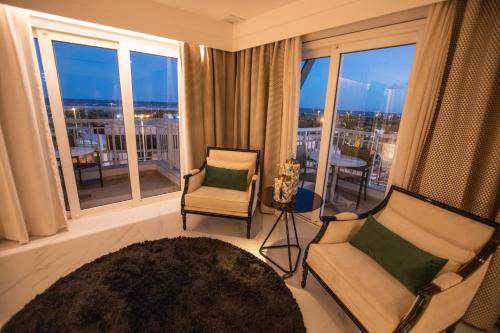a living room with two chairs and a large window at Vidam Hotel Aracaju - Transamerica Collection in Aracaju