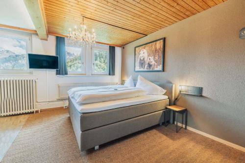 a bedroom with a bed and a chandelier at Gasthof Bären in Hasliberg