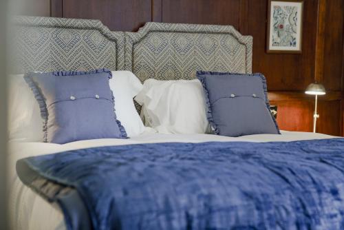 a bed with blue and white pillows on it at Bel and The Dragon at Red Lion Wendover in Wendover