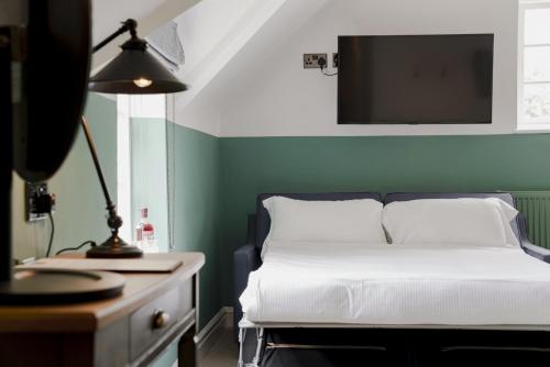 a bedroom with a bed and a desk with a television at Bel and The Dragon at Red Lion Wendover in Wendover