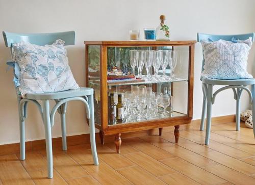 two chairs and a glass cabinet with wine glasses at Saronis Hotel Agistri - Adults Only in Skala