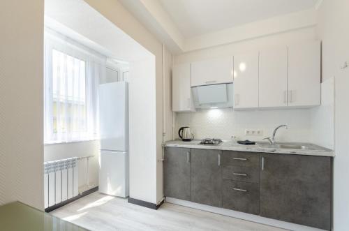a kitchen with white cabinets and a white refrigerator at ARTAL Apartment on Obolonskyi Avenue 16 in Kyiv
