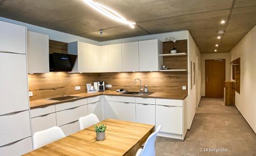 a kitchen with white cabinets and a wooden table at Boarding Apartments Kolbermoor in Kolbermoor