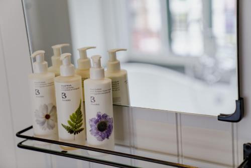 a group of four bottles of moisturizers on a glass shelf at Bel and The Dragon at Red Lion Wendover in Wendover