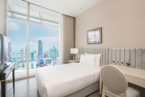 een slaapkamer met een bed, een bureau en een raam bij Magnolias Ratchadamri Boulevard Serviced Residences in Bangkok