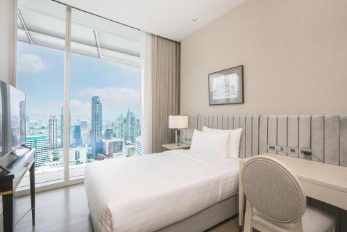 a bedroom with a bed and a desk and a window at Magnolias Ratchadamri Boulevard Serviced Residences in Bangkok