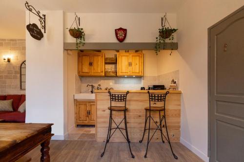 una cocina con armarios de madera y 2 taburetes de bar en Le Secret de la Taverne - Netflix/Wifi - Chasse Aux Trésor à l'intérieur, en Carcassonne