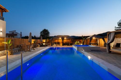 a large swimming pool with blue water at night at Panthea Luxury Villa in Ialysos