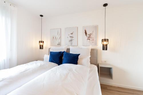 een slaapkamer met 2 witte bedden en blauwe kussens bij Modernes Apartment *Liobablick Nr. 3* - FeWo Fulda/Petersberg in Petersberg