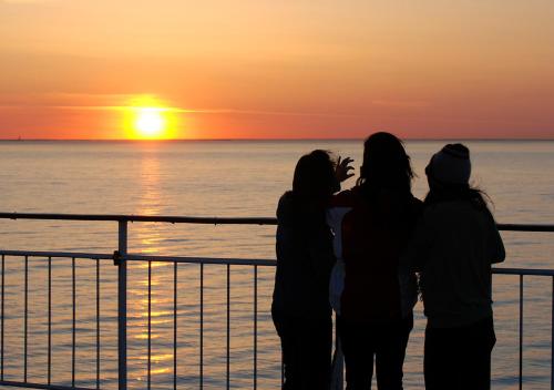 Tre donne in piedi su una nave da crociera che guardano il tramonto di Viking Line ferry Viking XPRS - Night Cruise from Helsinki a Helsinki