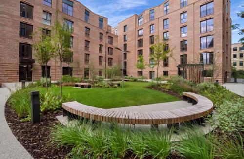 a garden with a circular bench in front of buildings at City Apartments - Hudson Quarter in York