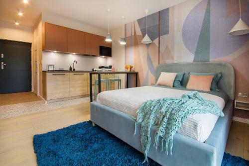 a bedroom with a blue bed and a kitchen at W&K Apartments - Joy Suite in Koszalin