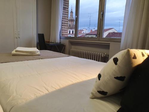 a bedroom with two beds and a large window at Pensión Muro de la Mata in Logroño