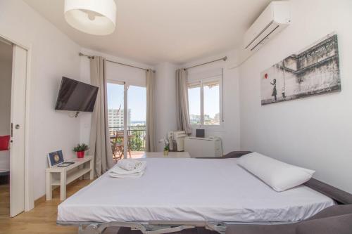 een slaapkamer met een wit bed en een televisie bij Santa Amalia 45 by IVI Real Estate in Torremolinos