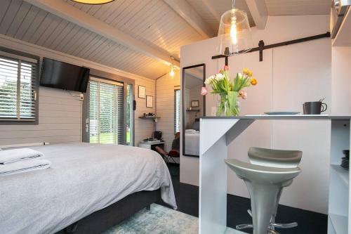 een slaapkamer met een bed en een vaas met bloemen bij Tiny House Boatshed in Heemstede