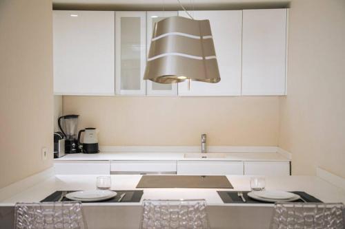 - une cuisine avec des placards blancs, un évier et des chaises dans l'établissement Coeur De Cannes, à Cannes