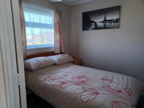 um quarto com uma cama com uma colcha de rosa vermelha em alicias chalets em Great Yarmouth