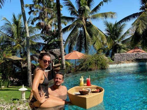 Un uomo e una donna seduti in piscina di Puri Dajuma Beach Eco-Resort & Spa a Pulukan