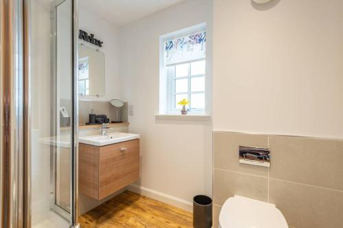 a bathroom with a toilet and a sink and a window at Stylish & Modern Apartment in Inverness