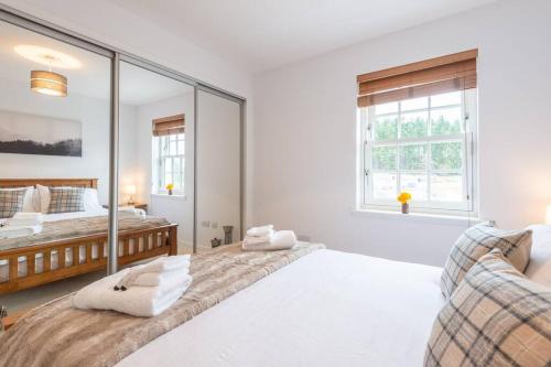 a white bedroom with two beds and a mirror at Stylish & Modern Apartment in Inverness