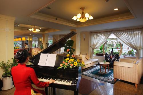 a woman playing a piano in a living room at First Hotel in Ho Chi Minh City