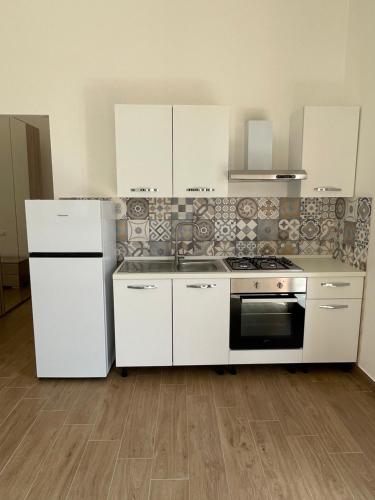 een keuken met witte apparatuur en een houten vloer bij Aria case vacanze in Favignana