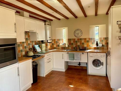 a kitchen with white cabinets and a washing machine at Farriers Cottage in Grantham