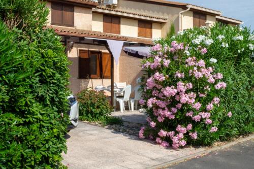 a house with a flower garden and a pink umbrella at Les Tamaris et Les Portes du Soleil in Portiragnes