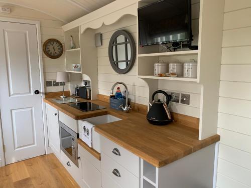 een keuken met witte kasten, een wastafel en een klok bij Weatherhead Farm in Buckingham