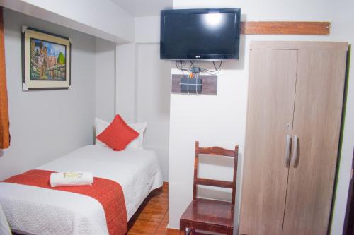 a small room with a bed and a tv on the wall at Machu Picchu Land in Machu Picchu