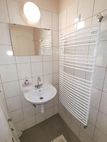a white bathroom with a sink and a mirror at Kamilla Panzió és Rendezvényház in Balmazújváros
