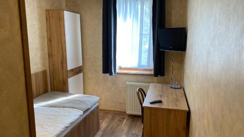 a room with a bed and a desk with a television at Penzión pri Kaštieli in Bratislava