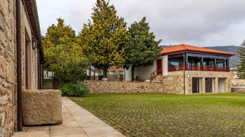 a house with a stone wall next to a yard at Hotel Rural Quinta de Sao Sebastiao in Barroselas
