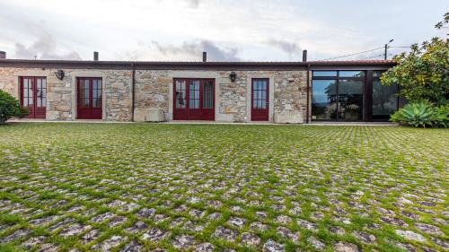 a stone house with red doors and a yard at Hotel Rural Quinta de Sao Sebastiao in Barroselas