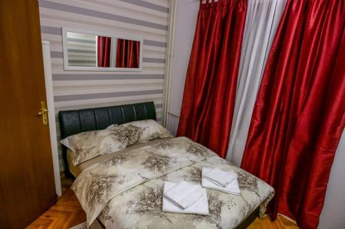 una piccola camera con letto e tende rosse di Silver a Žarkovo