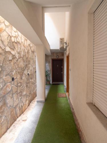 a hallway with green flooring and a stone wall at Mum's Apartment in Petrovac na Moru