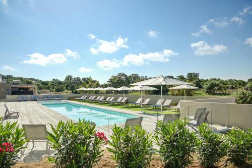 a swimming pool with lounge chairs and umbrellas at Résidence Pierre & Vacances Premium Les Terrasses d'Arsella in Porto-Vecchio