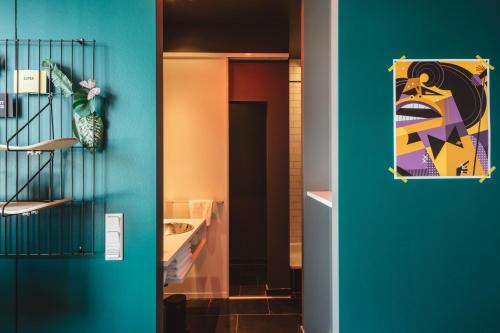 a hallway with a blue wall with a painting on the wall at Superbude Hamburg Altona in Hamburg