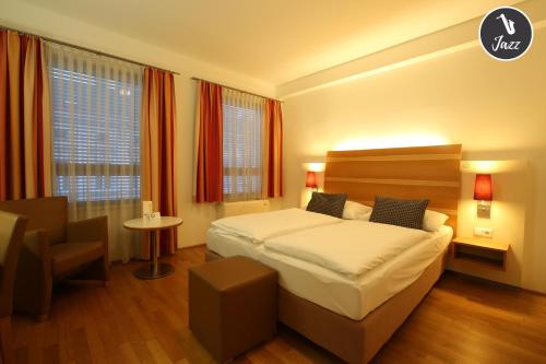 a bedroom with a bed and a table and a chair at arte Hotel Wien Stadthalle in Vienna