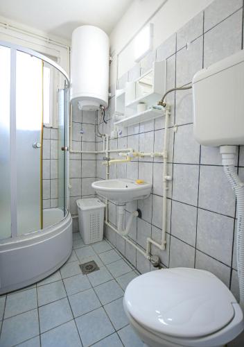 a white bathroom with a toilet and a sink at Apartman 59 in Kladovo