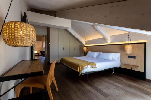 Un dormitorio con una cama, una mesa y un escritorio. en No-Mad Green Hotel, en Molinaseca