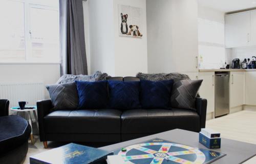 a living room with a black couch and a table at Didcot - Private Flat with Garden & Parking 07 in Didcot