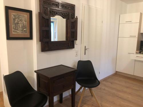 Zimmer mit 2 Stühlen, einem Tisch und einem Spiegel in der Unterkunft See Appartements in Mörbisch am See